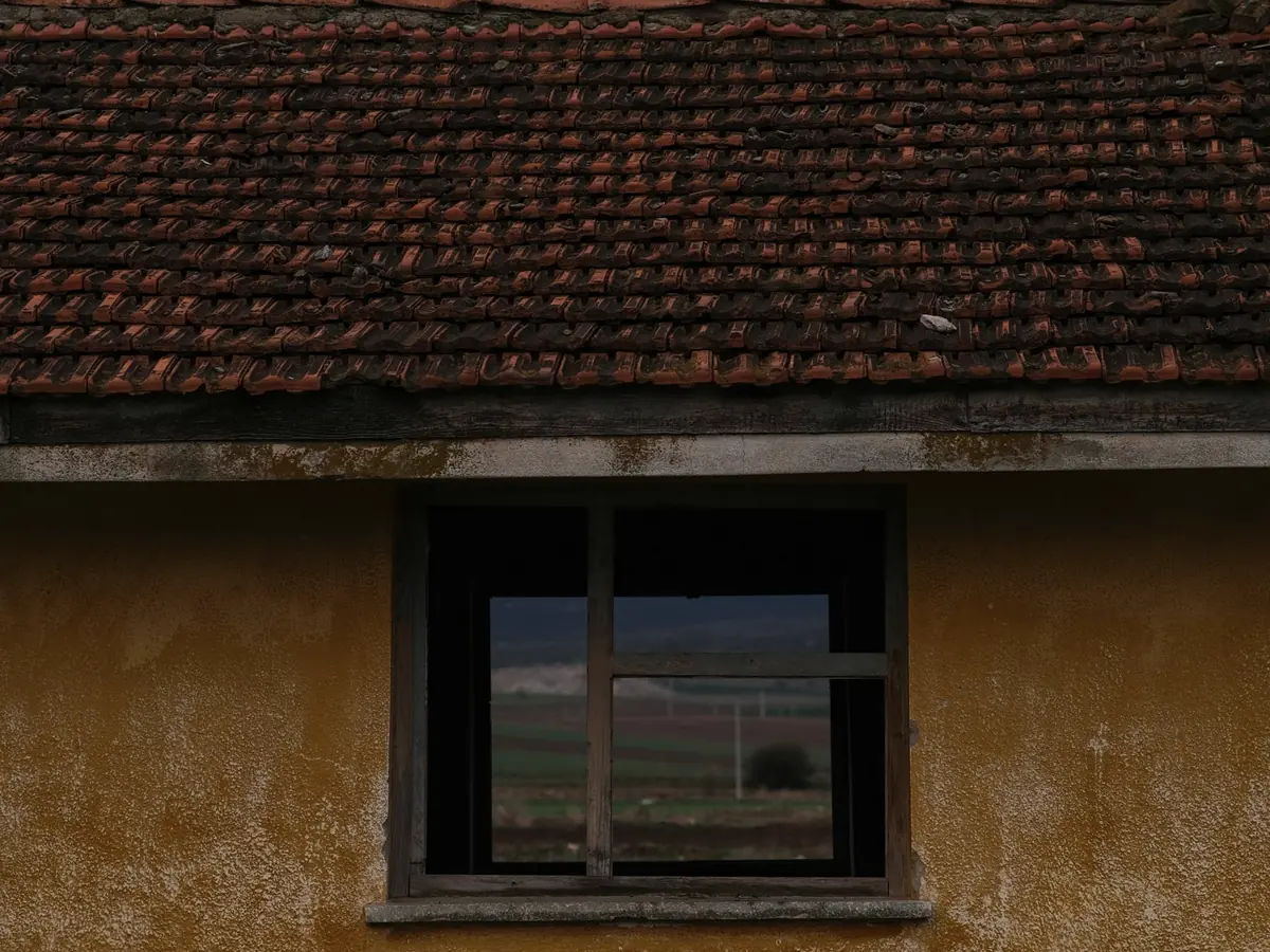 Fachada antiga de casa com telhado de barro e janela de madeira