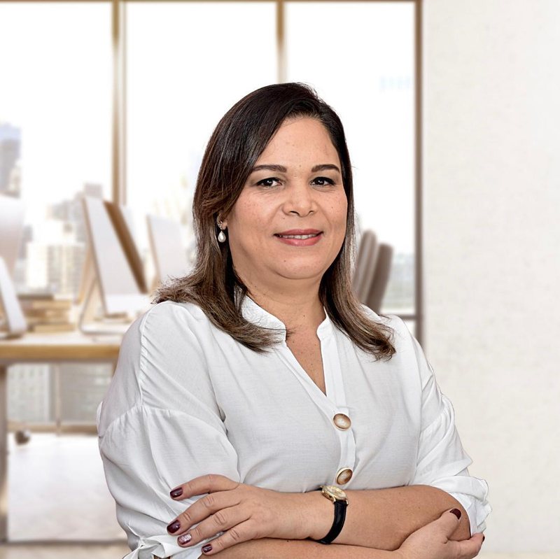 Dra. Luciana Lima, advogada, de braços cruzados e sorrindo, em um escritório claro