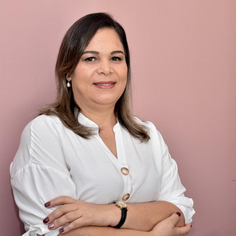 Retrato da Dra. Luciana Lima, advogada, de camisa branca e braços cruzados